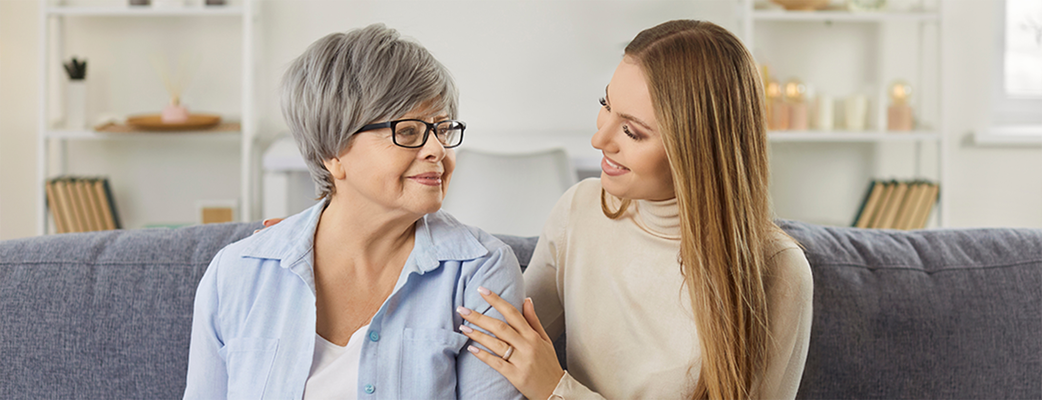 Image of a senior woman sitting on the sofa with a middle-aged woman